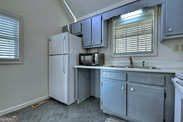 kitchen featuring visible vents, a sink, freestanding refrigerator, black microwave, and light countertops