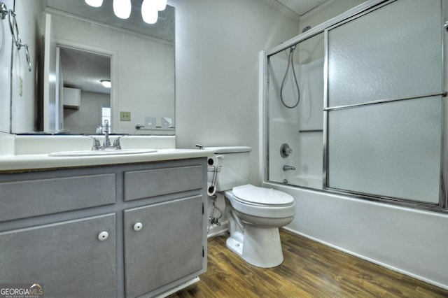 bathroom featuring shower / bath combination with glass door, toilet, wood finished floors, and vanity