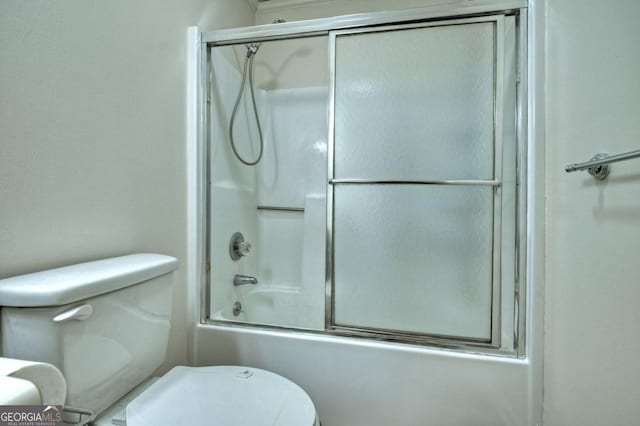 bathroom featuring toilet and bath / shower combo with glass door