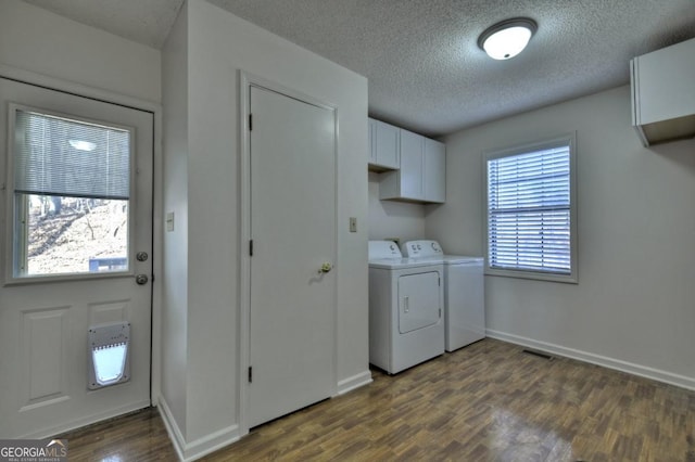 clothes washing area featuring dark wood-style floors, washing machine and dryer, cabinet space, and baseboards