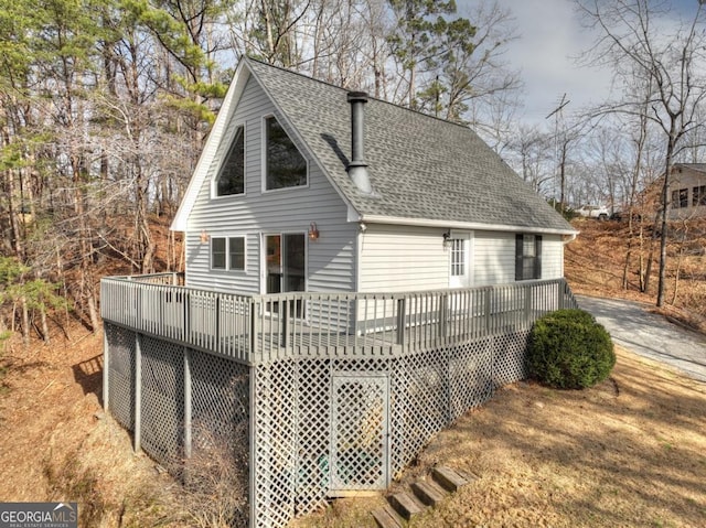 rear view of property featuring a deck and a shingled roof