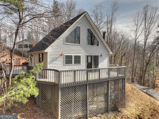 rear view of property featuring a chimney and a wooden deck