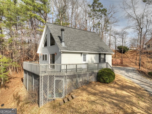 back of property with roof with shingles and a wooden deck