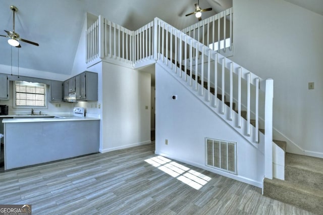 kitchen featuring a ceiling fan, visible vents, high vaulted ceiling, gray cabinetry, and range