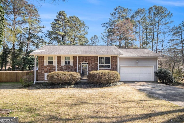 view of front of home featuring brick siding, fence, a front yard, a garage, and driveway