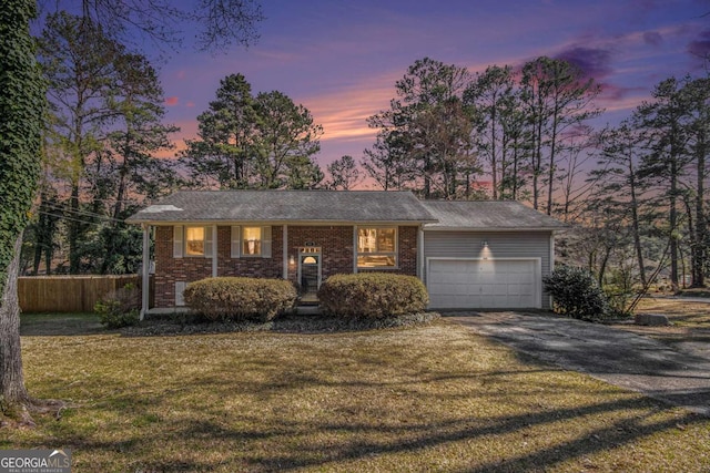 view of front facade with brick siding, fence, aphalt driveway, a front yard, and an attached garage