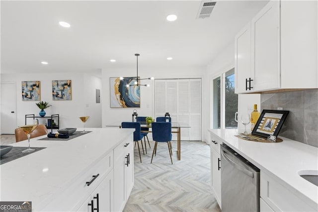 kitchen with stainless steel dishwasher, decorative backsplash, white cabinets, and visible vents