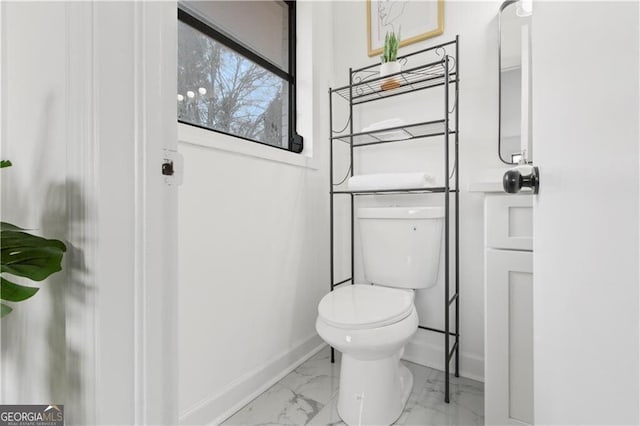 bathroom with toilet, baseboards, and marble finish floor