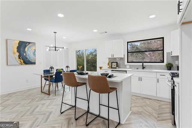 kitchen with a sink, stainless steel appliances, a kitchen bar, and a wealth of natural light