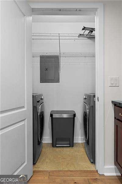 laundry room featuring washer / dryer, electric panel, light wood-type flooring, and laundry area