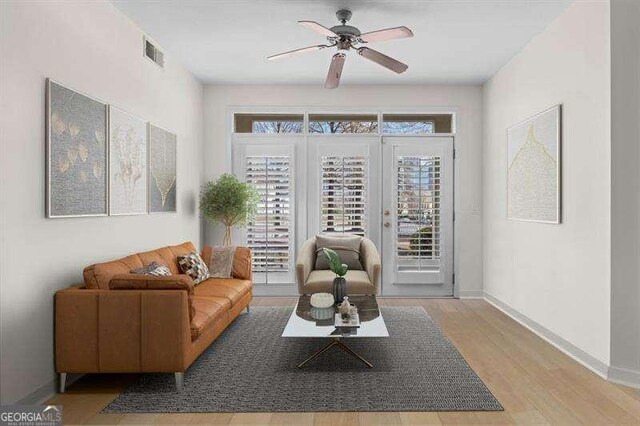 living room with wood finished floors, baseboards, visible vents, ceiling fan, and french doors