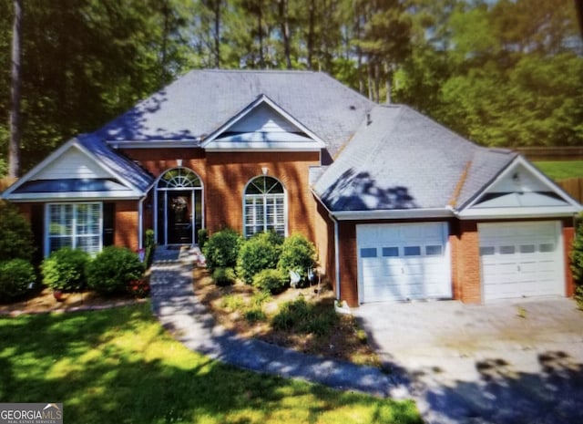 view of front of home featuring a garage, a front lawn, brick siding, and driveway