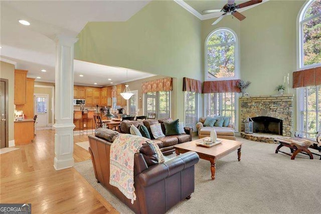 living room with a wealth of natural light, decorative columns, a ceiling fan, and crown molding