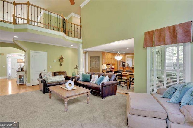 living room with crown molding, baseboards, decorative columns, wood finished floors, and arched walkways