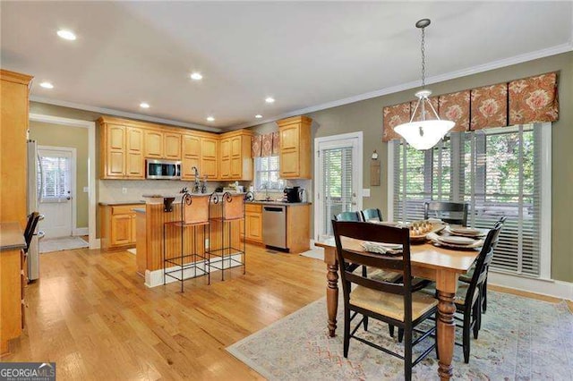 dining space featuring a healthy amount of sunlight, crown molding, and light wood-type flooring