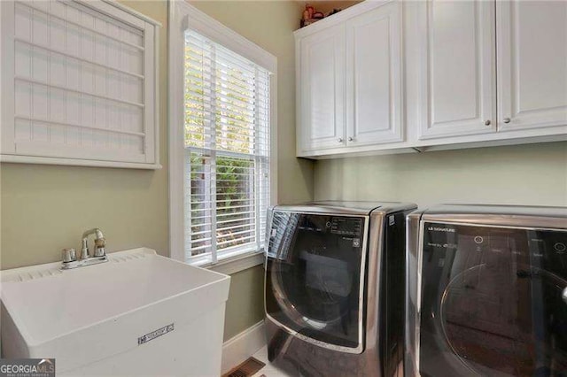 washroom with cabinet space, independent washer and dryer, baseboards, and a sink