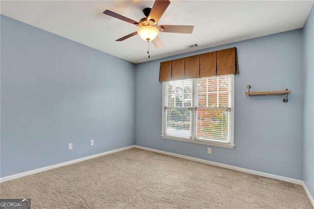 carpeted empty room with visible vents, a ceiling fan, and baseboards