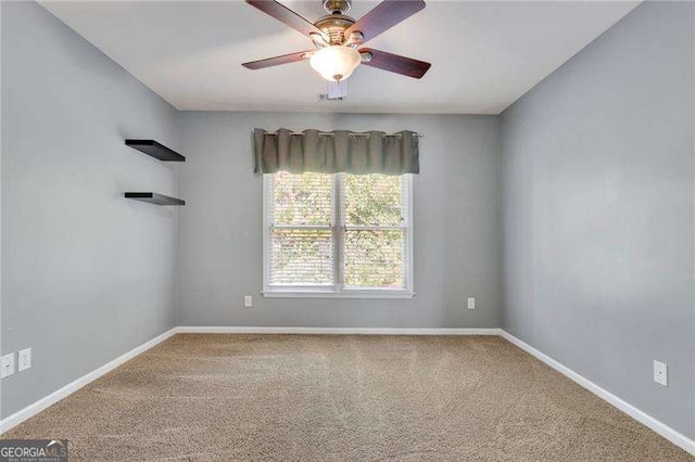 carpeted empty room featuring a ceiling fan and baseboards