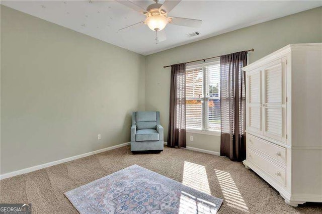 living area featuring visible vents, baseboards, light colored carpet, and a ceiling fan