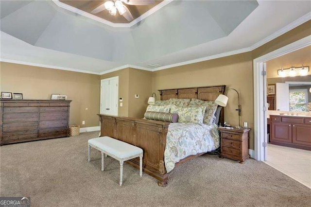 bedroom featuring a raised ceiling, light colored carpet, ensuite bathroom, and crown molding