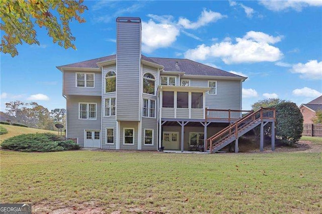 back of house with stairway, a lawn, a chimney, a deck, and a sunroom