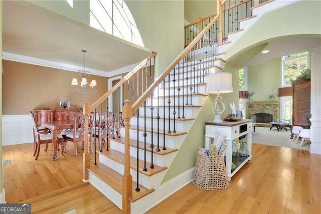 stairway with arched walkways, a fireplace, crown molding, and wood finished floors