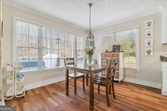 dining area featuring a textured ceiling, wood finished floors, and ornamental molding