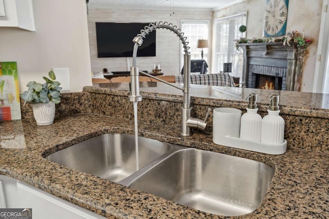 details with a brick fireplace, stone counters, and a sink