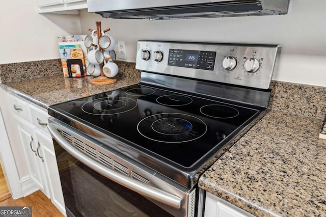 room details with stainless steel electric stove, light wood-style flooring, and white cabinetry