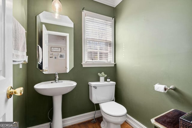 half bath with a sink, baseboards, toilet, and wood finished floors