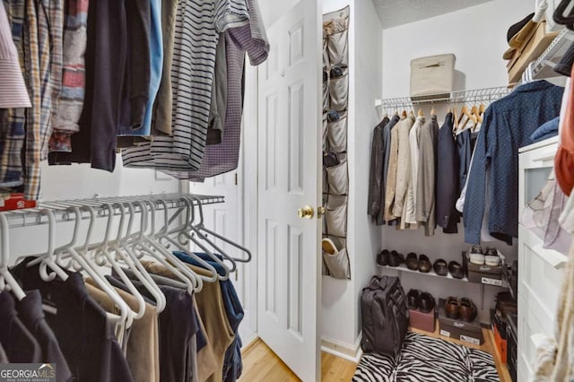 walk in closet with wood finished floors