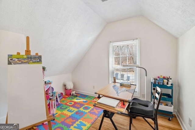 game room with baseboards, a textured ceiling, wood finished floors, and vaulted ceiling