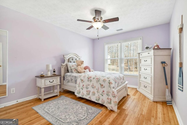 bedroom featuring a textured ceiling, baseboards, light wood-style floors, and a baseboard radiator