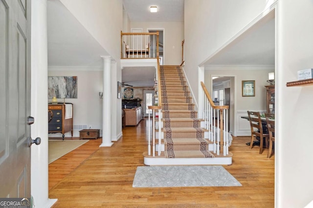 entrance foyer featuring stairway, wood finished floors, a towering ceiling, and ornamental molding