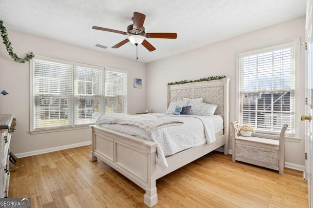 bedroom featuring a ceiling fan, light wood-style floors, visible vents, and baseboards