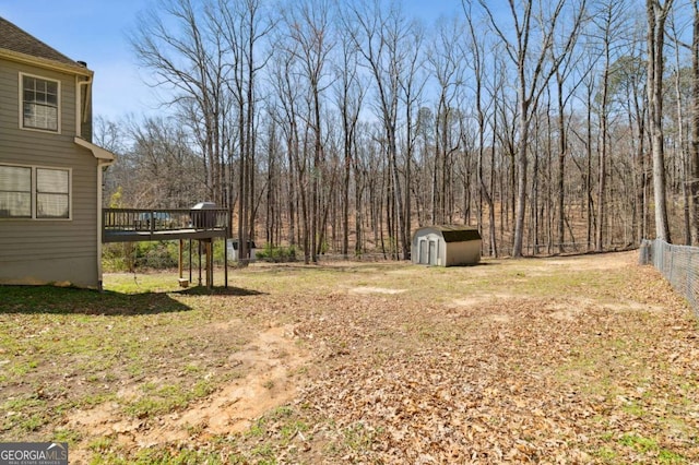 view of yard featuring fence, an outdoor structure, a deck, and a shed