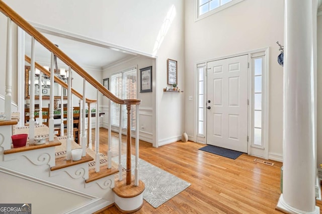 foyer entrance featuring stairs, plenty of natural light, wood finished floors, and visible vents