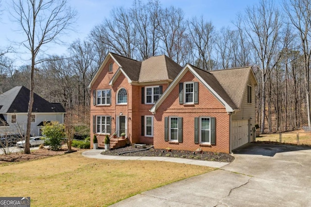 colonial inspired home with a front yard, driveway, an attached garage, a shingled roof, and brick siding