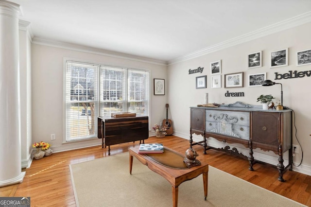 sitting room with crown molding, light wood finished floors, baseboards, and ornate columns