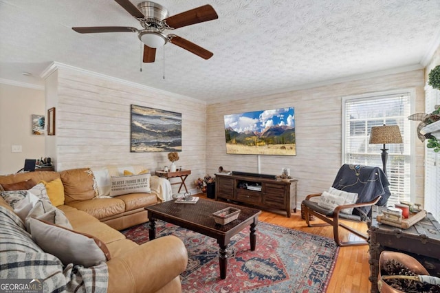 living area featuring a textured ceiling, crown molding, hardwood / wood-style flooring, and ceiling fan