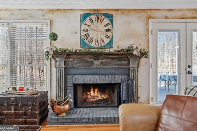 sitting room featuring french doors, a brick fireplace, wood finished floors, and crown molding