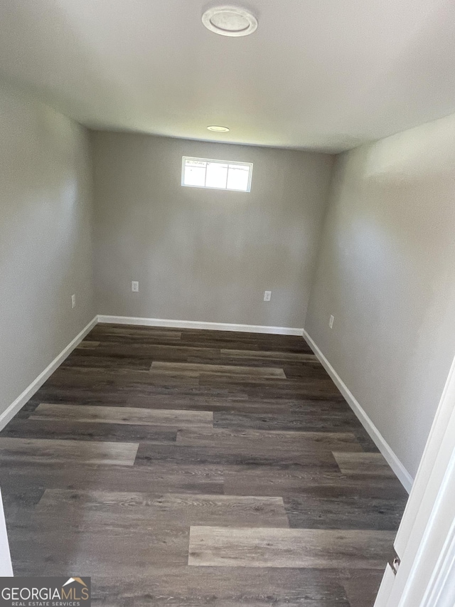 basement featuring baseboards and dark wood-type flooring