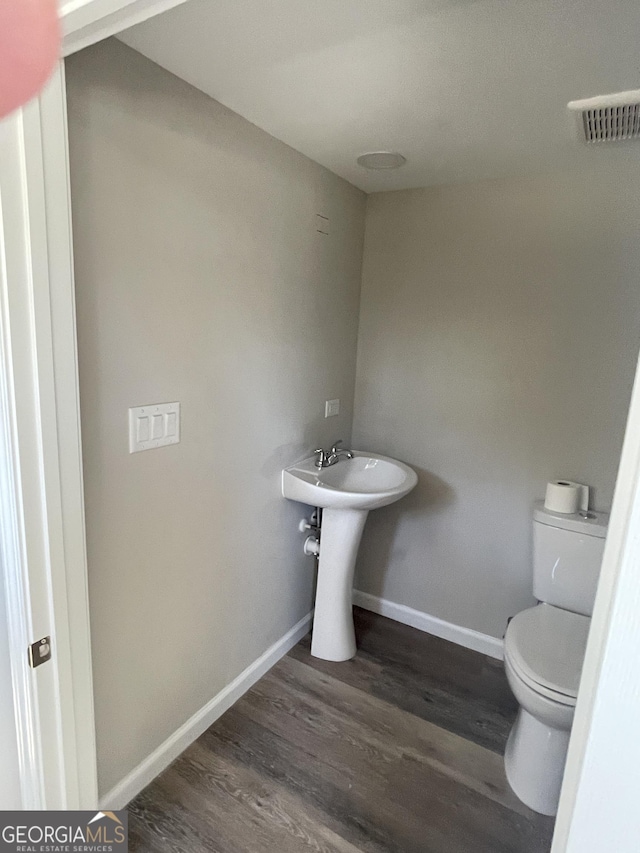 half bathroom featuring visible vents, toilet, baseboards, and wood finished floors