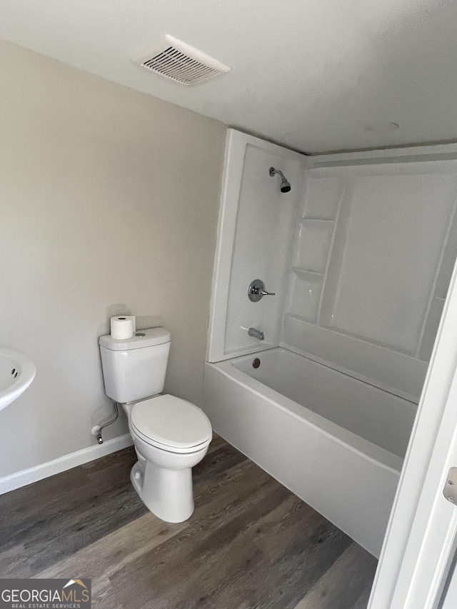 bathroom with visible vents, baseboards, toilet, wood finished floors, and  shower combination