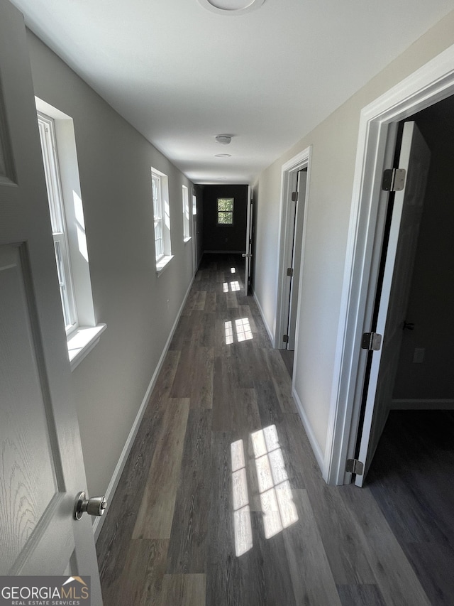 hall with baseboards and wood finished floors