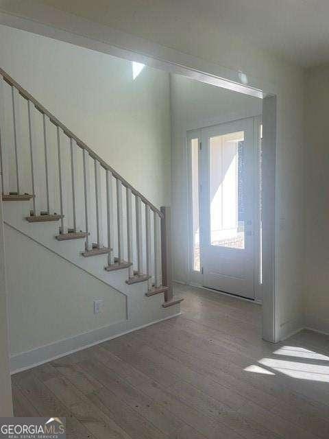 entrance foyer with stairs, wood finished floors, and baseboards