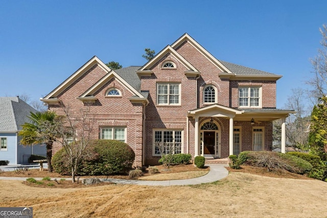 view of front of home with brick siding, a front lawn, and a shingled roof