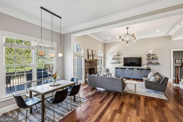 dining room featuring a chandelier, a stone fireplace, dark wood finished floors, and ornamental molding