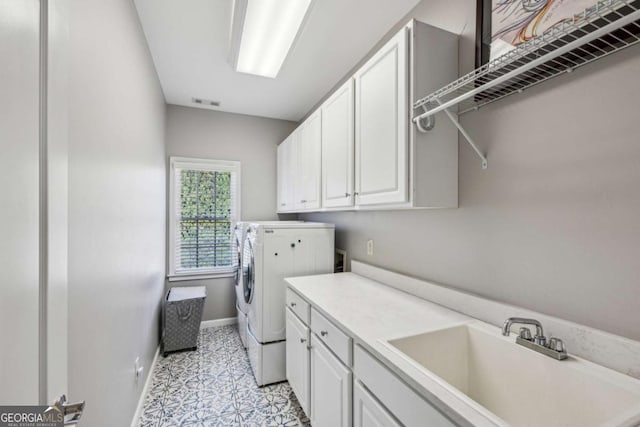 laundry area with visible vents, a sink, washing machine and dryer, cabinet space, and baseboards