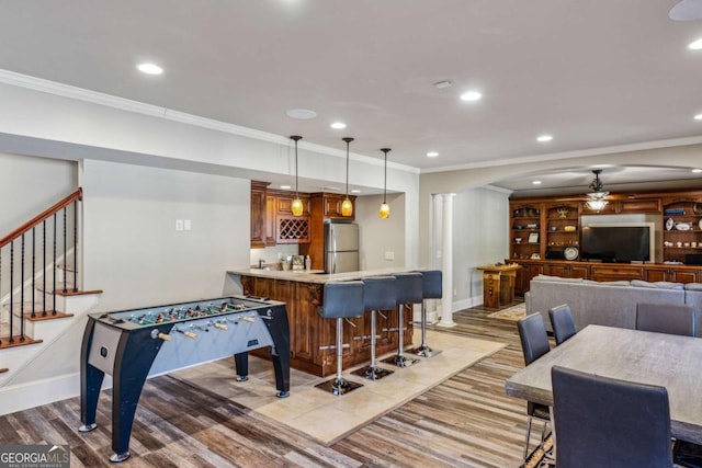 recreation room featuring ceiling fan, wet bar, ornamental molding, and recessed lighting